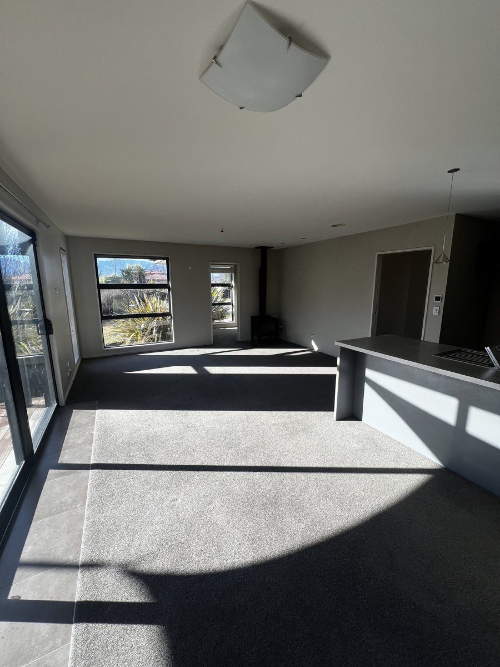 Freshly painted interior living room with white ceiling, neutral taupe walls, and large windows overlooking garden at Albert Town, Wanaka.