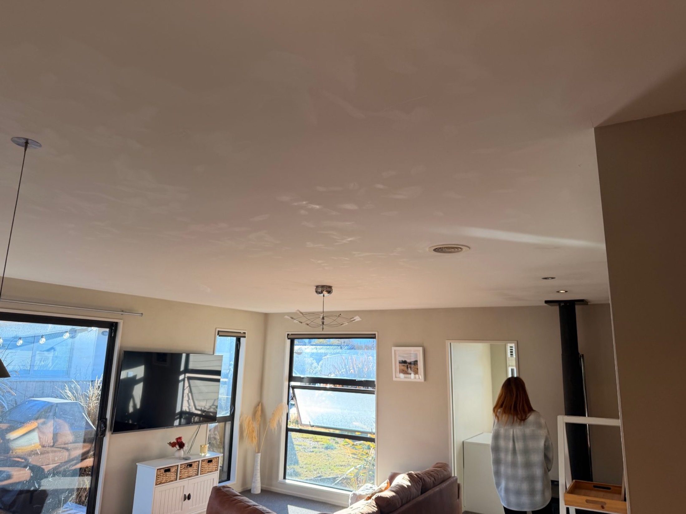Interior living room with cream and white walls, white ceiling, and large windows overlooking landscape at Albert Town property before painting prep.